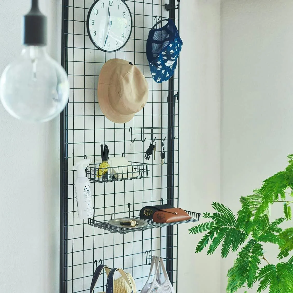 Hình nền chill với kệ lưới tối giản, đồng hồ treo tường, mũ thời trang và cây dương xỉ xanh trong căn phòng sáng màu