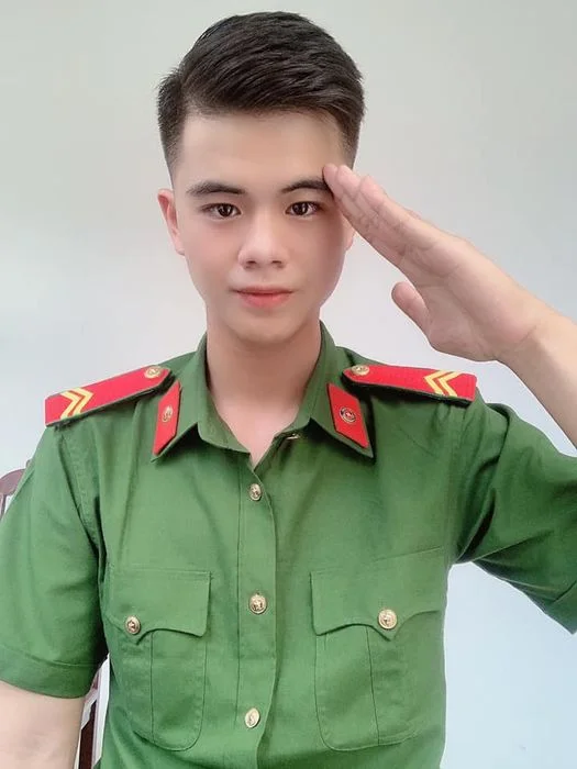 Nam chiến sĩ công an trẻ mặc đồng phục thực hiện động tác chào