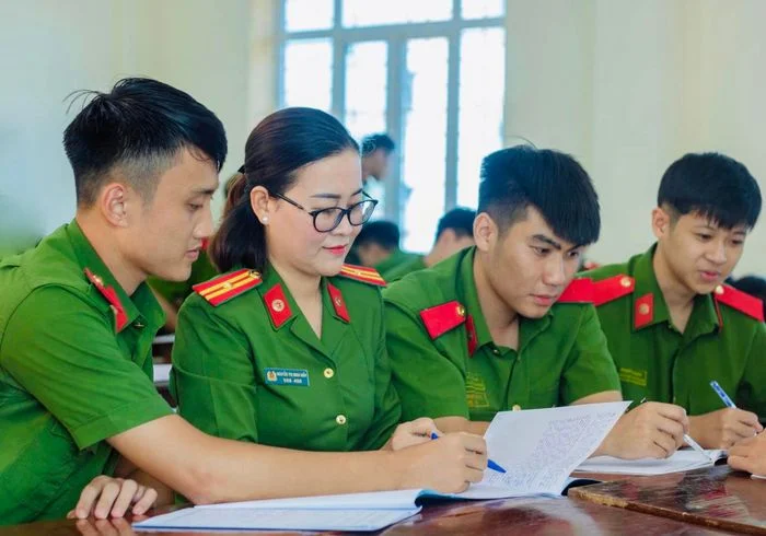 Các chiến sĩ công an mặc đồng phục xanh cùng làm việc với hồ sơ trên bàn