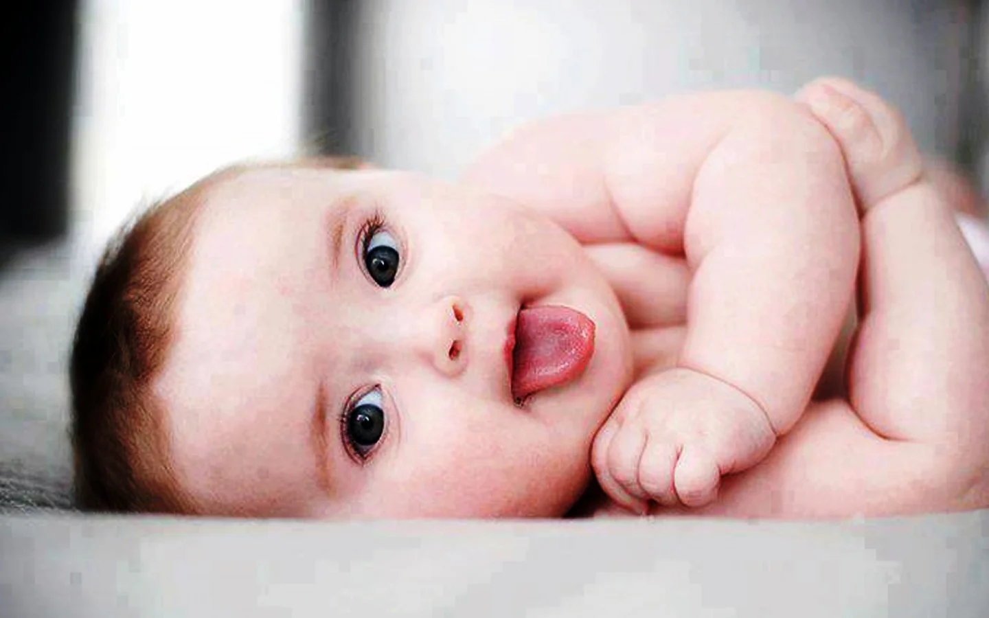 Ảnh em bé dễ thương đang thè lưỡi nhìn vào ống kính